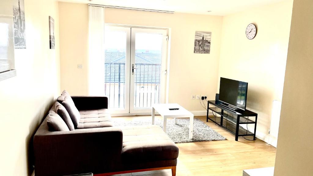 uma sala de estar com um sofá e uma televisão em Holiday Flat in Central Slough near to London Heathrow and Windsor with Free Car Park em Slough