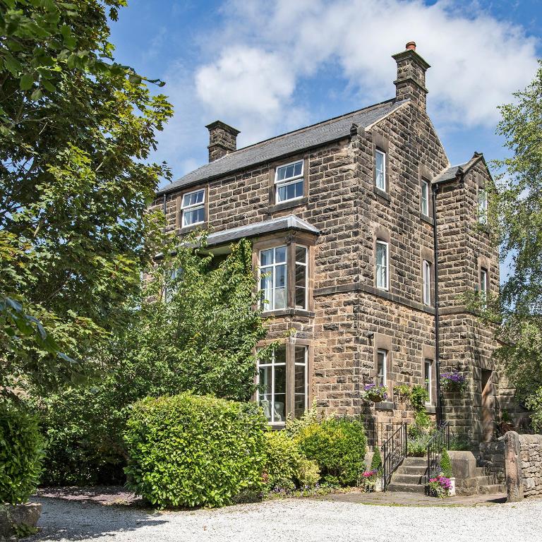 an old brick house with bushes in front of it at Sheriff Lodge in Matlock