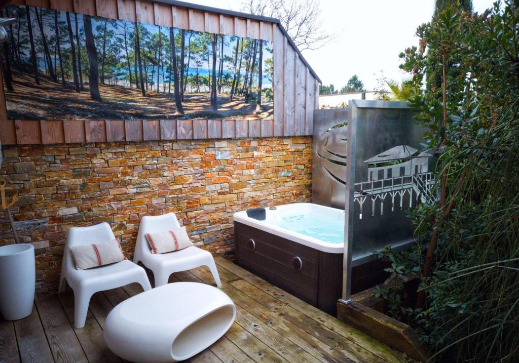 La salle de bains est pourvue d'une baignoire et de 2 chaises sur une terrasse. dans l'établissement L'Essentiel, à Gujan-Mestras