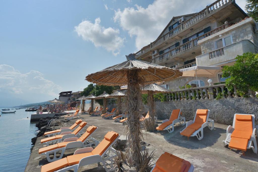 a group of lounge chairs and an umbrella on a beach at Apartments Palace Mira Mare in Tivat