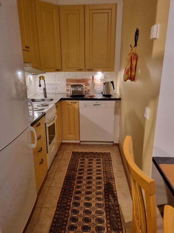 eine Küche mit weißen Geräten und einem Teppich auf dem Boden in der Unterkunft Apartment Oulu Varjakka in Oulunsalo
