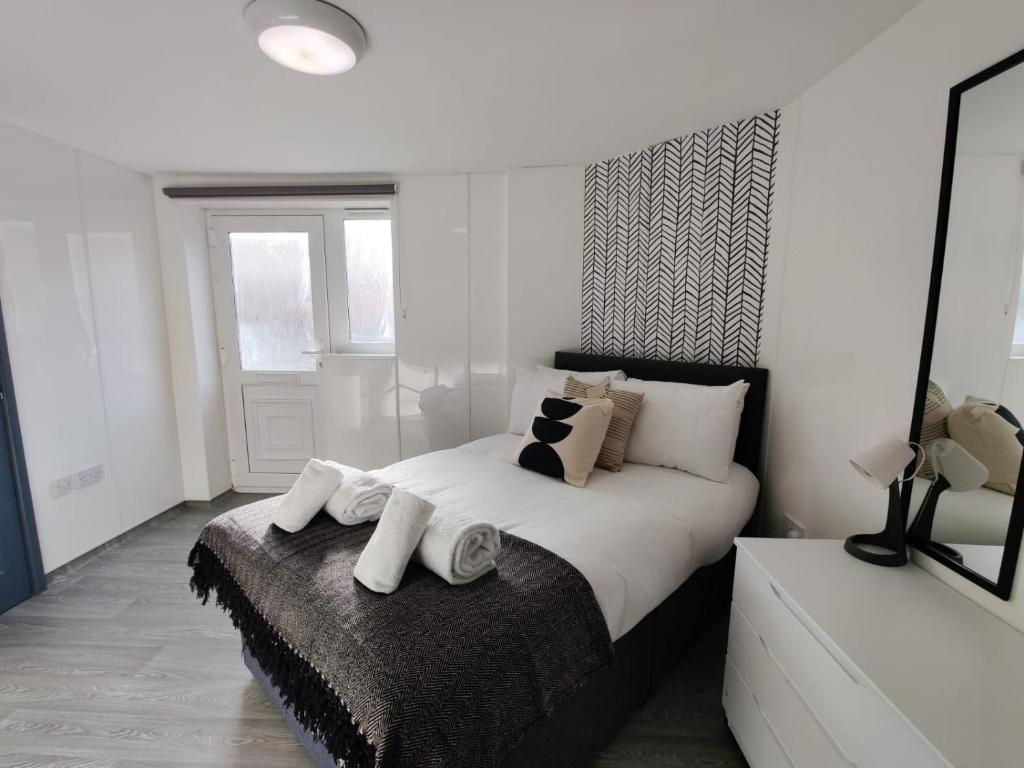 een witte slaapkamer met een groot bed met handdoeken erop bij Stop Stay at The Osterley! in Swansea