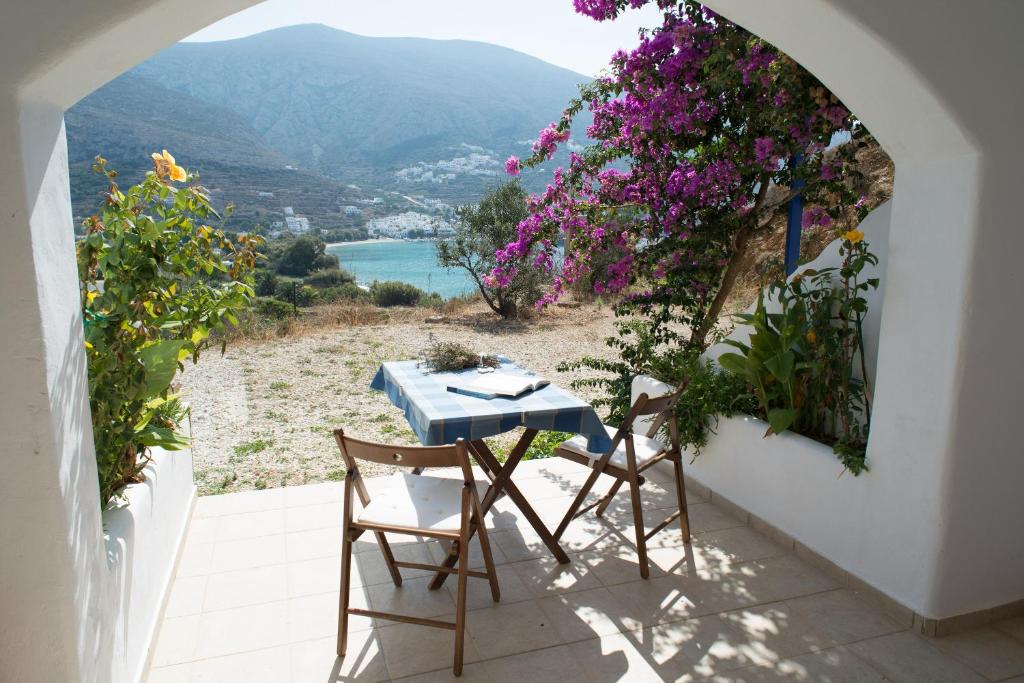 a table and chairs on a balcony with flowers at Amorgi Studios in Aegiali
