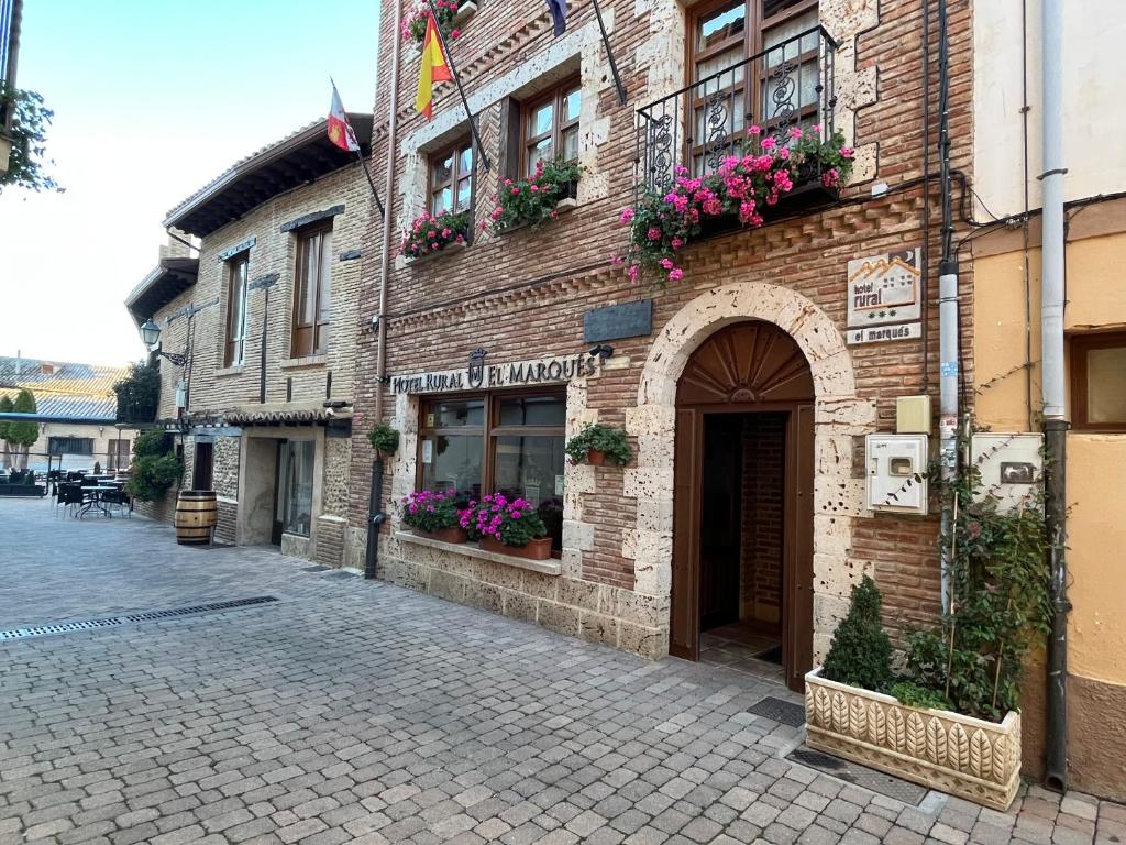a brick building with flower boxes on a street at Hotel Rural El Marqués in Saldaña