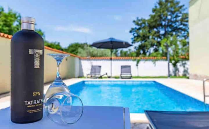 uma garrafa de vinho sentada numa mesa ao lado de uma piscina em Apartments EDEN em Sisan