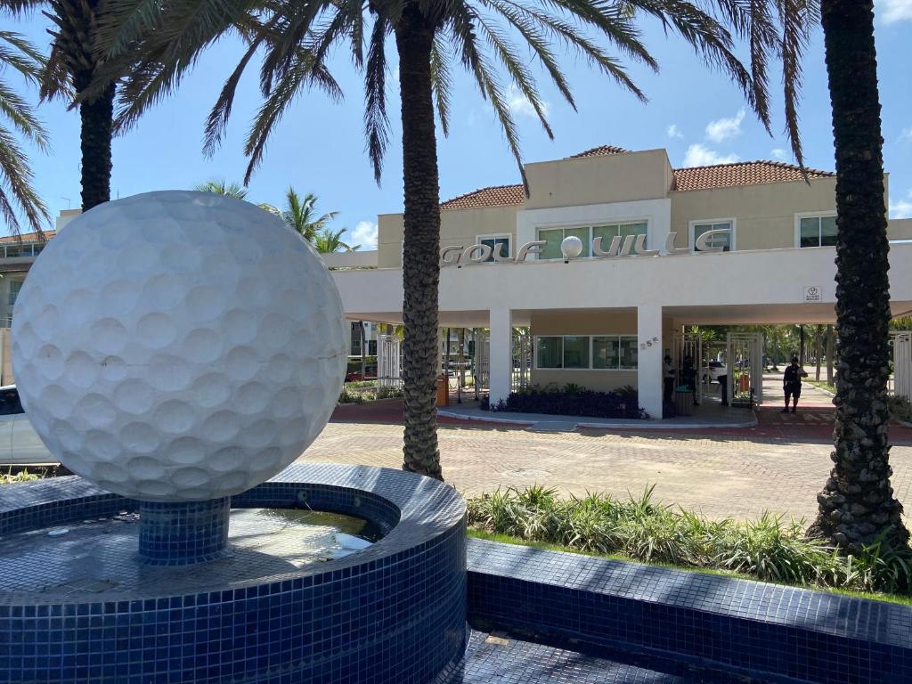 a golf ball in front of a building with palm trees at Conforto e Lazer no Golf Ville Resort Alto Padrão in Aquiraz