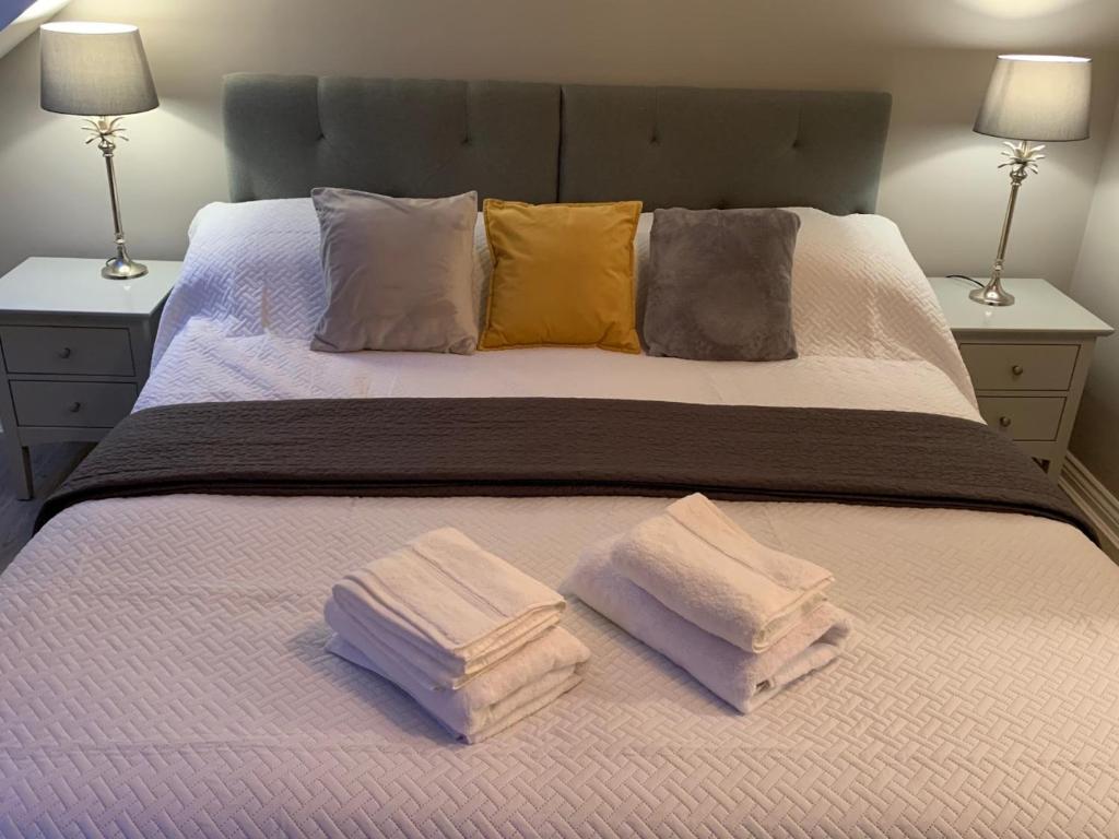 a bed with three towels on it with two lamps at Column Mews Townhouse in Alnwick