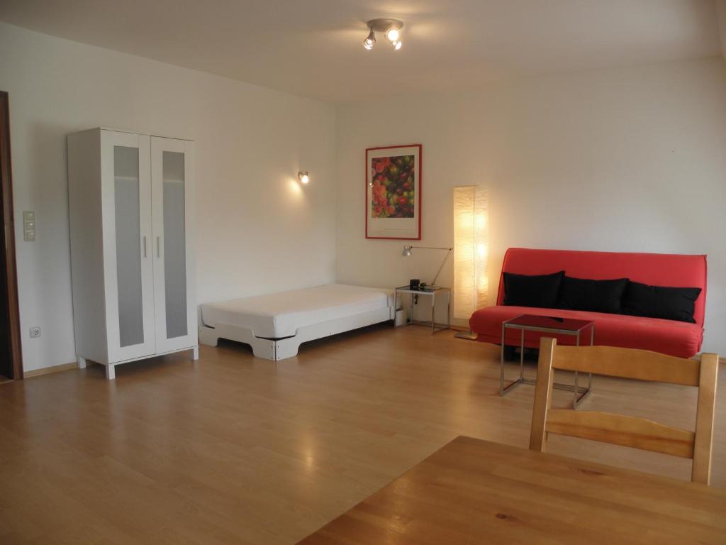 ein Wohnzimmer mit einem roten Sofa und einem Tisch in der Unterkunft Dependance am Blumenbrunnen in Baden-Baden