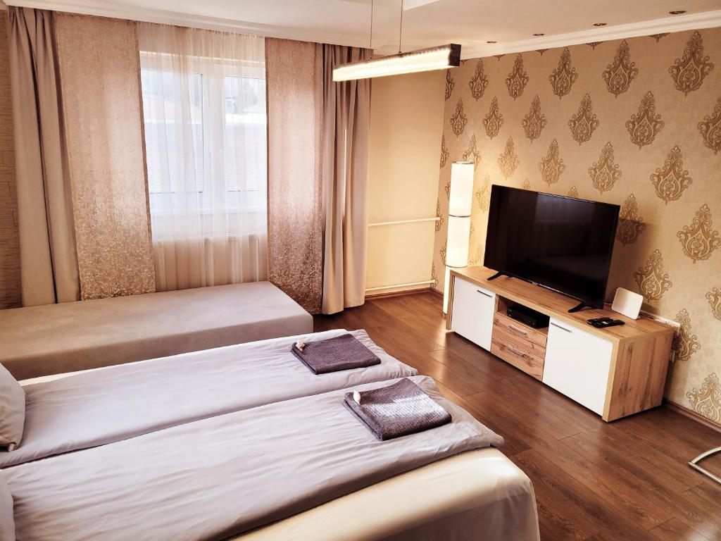 a hotel room with two beds and a flat screen tv at Indira Vendégház in Nyíregyháza