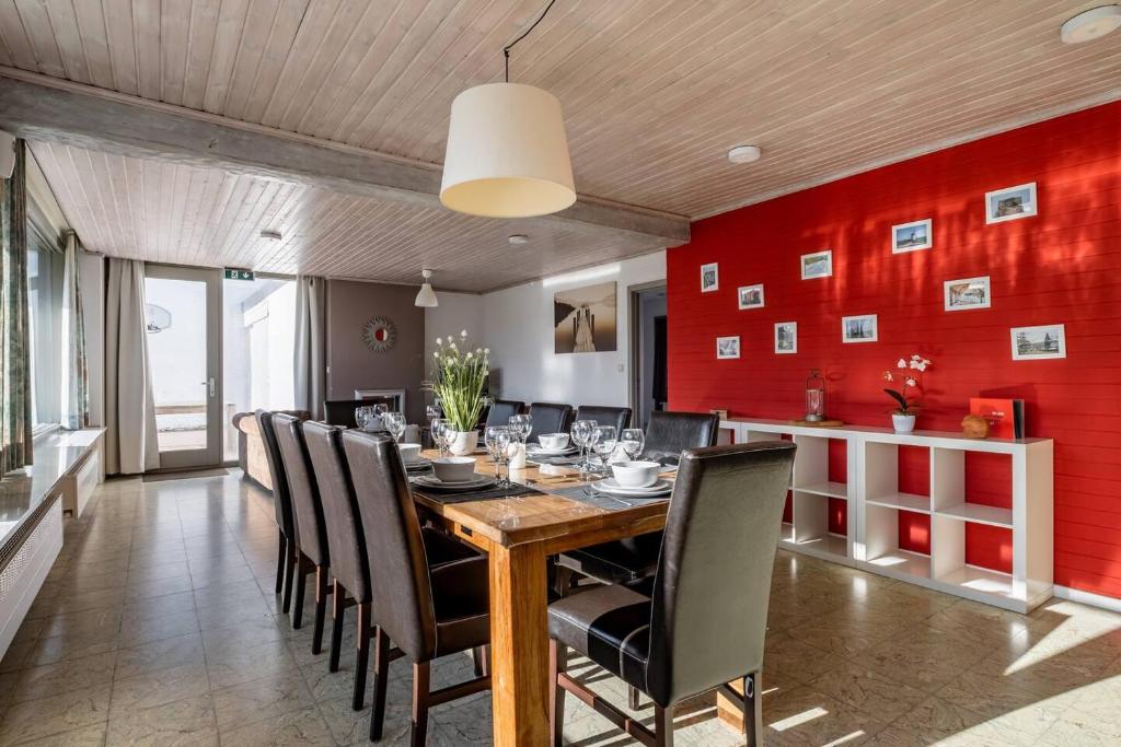 uma sala de jantar com paredes vermelhas e uma mesa e cadeiras de madeira em Flanders Fields Cottage em Beveren