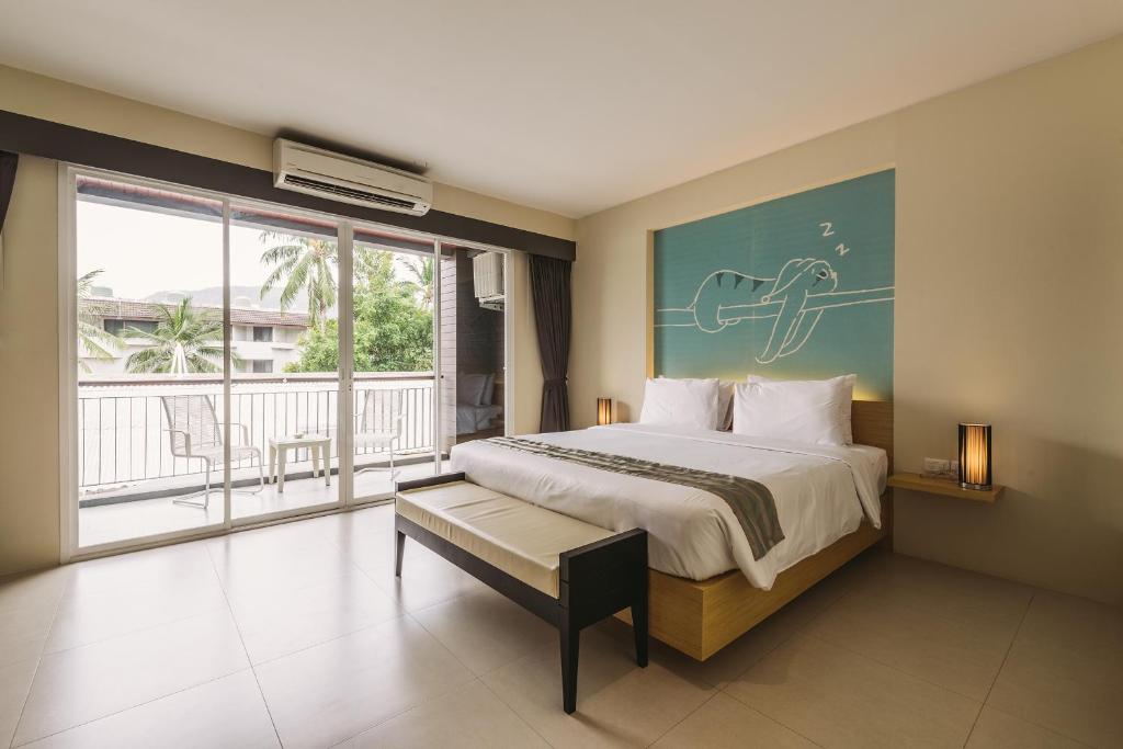 Un dormitorio con una cama grande y un balcón. en TIRAS Patong Beach Hotel, en Patong Beach