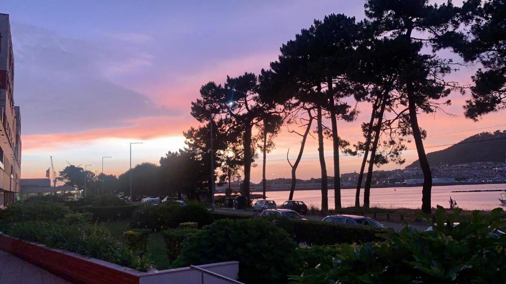 un coucher de soleil sur un parking avec des arbres et une rivière dans l'établissement Divine Waves - Cabedelo, à Viana do Castelo