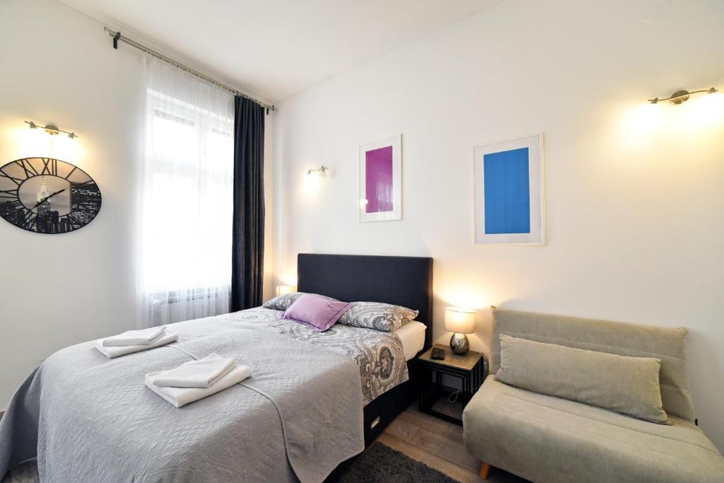ein Schlafzimmer mit einem Bett, einem Stuhl und einer Uhr in der Unterkunft Deluxe Apartments Ria in Zagreb
