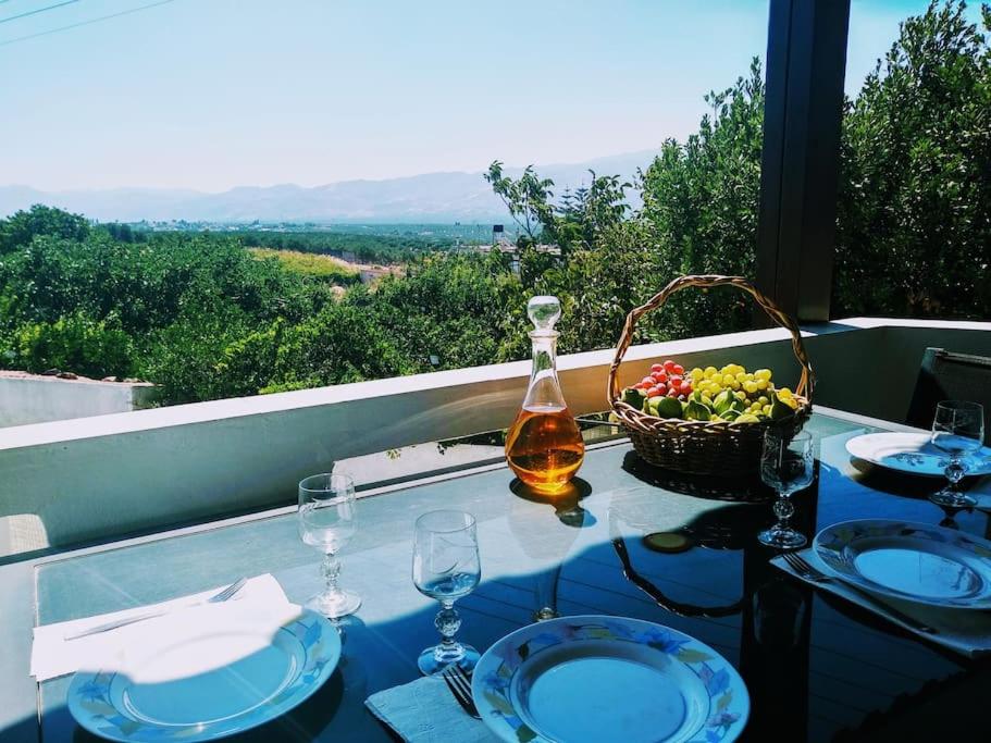 un tavolo con una bottiglia di vino e un cesto di frutta di Green Garden House a Stóloi