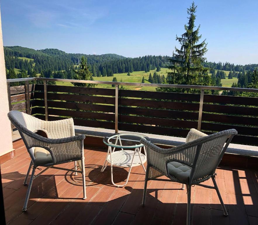 three chairs and a table on a deck with a view at Happy Place in Poiana Brasov