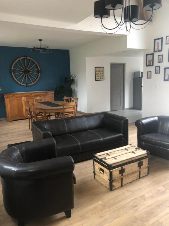 a living room with black leather furniture and a table at Maison chaleureuse à la campagne in Camps-en-Amiénois