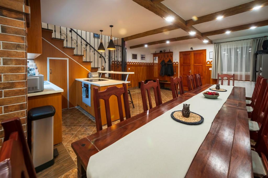 a kitchen and dining room with a long table and chairs at Baglyas Vendégház in Edelény