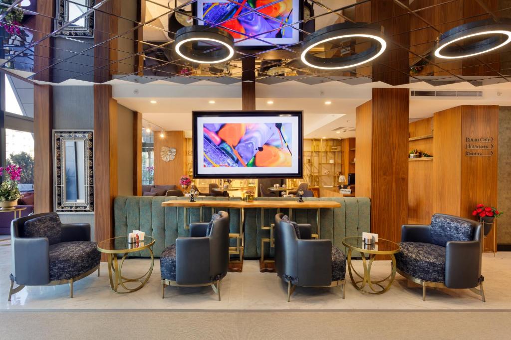 a lobby with a tv and chairs and tables at Buem Hotel Koşuyolu in Istanbul