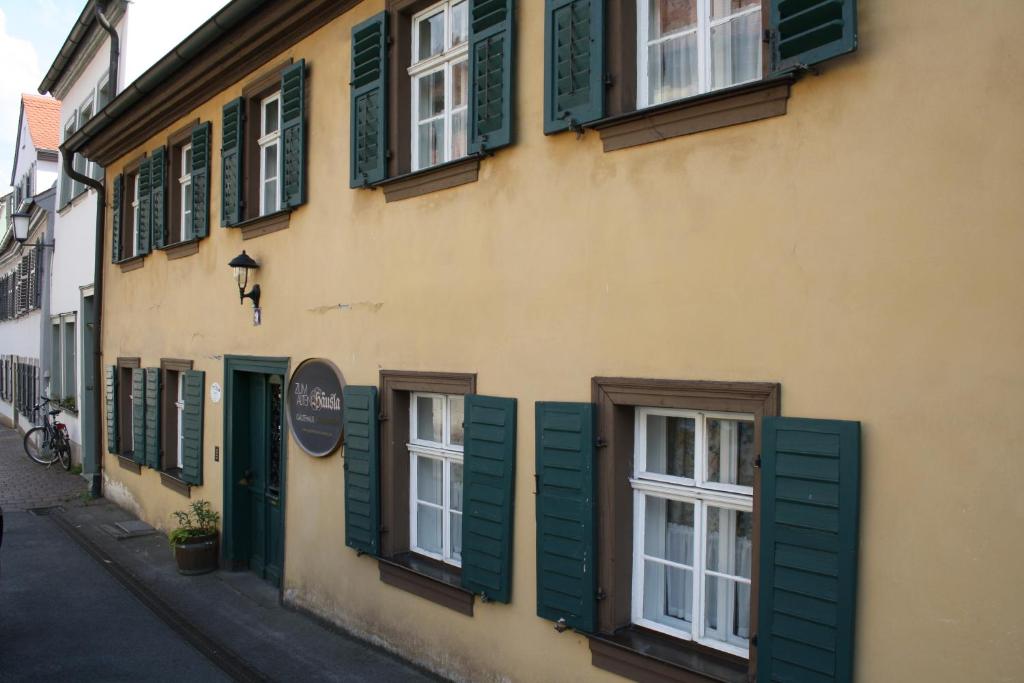 ein gelbes Gebäude mit grünen Rollläden auf einer Straße in der Unterkunft Zum alten Häusla in Bamberg