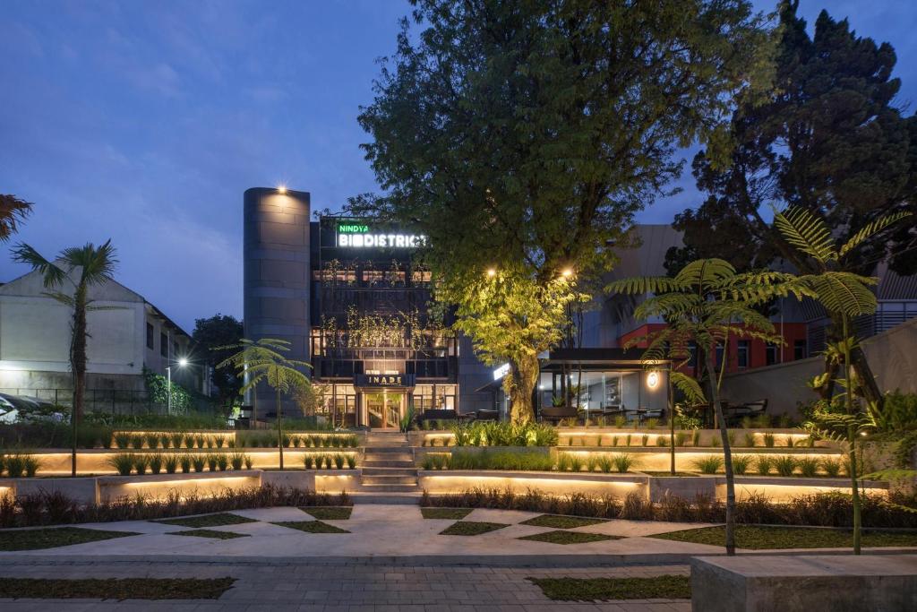 un edificio con un albero e luci di fronte ad esso di Nindya Biodistrict Hotel Bandung a Bandung