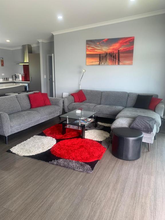 a living room with a couch and a red rug at Hosts on the Coast Belair Bach in Whitianga