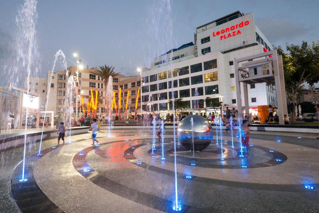 a fountain in the middle of a city with buildings at Leonardo Plaza Netanya Hotel in Netanya