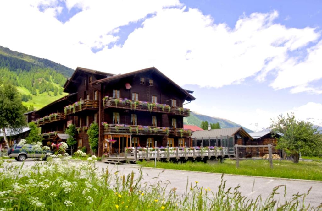 um grande edifício de madeira com uma varanda nas montanhas em Swiss Lodge Joopi em Reckingen - Gluringen