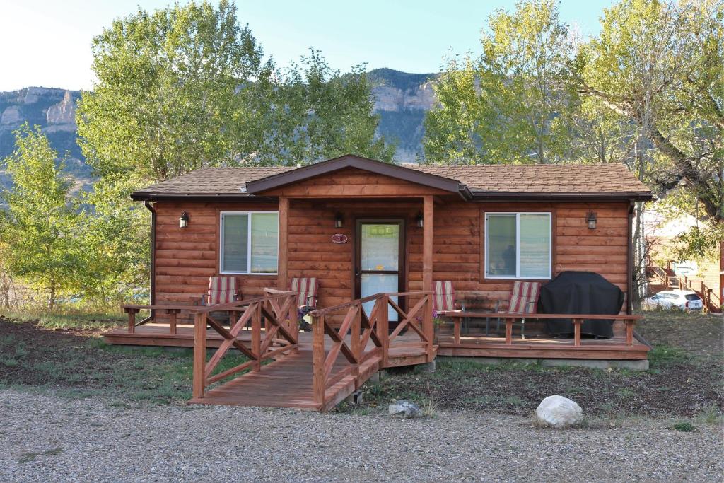 a cabin with chairs and a porch with a mountain in the background at Eycat Lodging Company Guest House in Wapiti