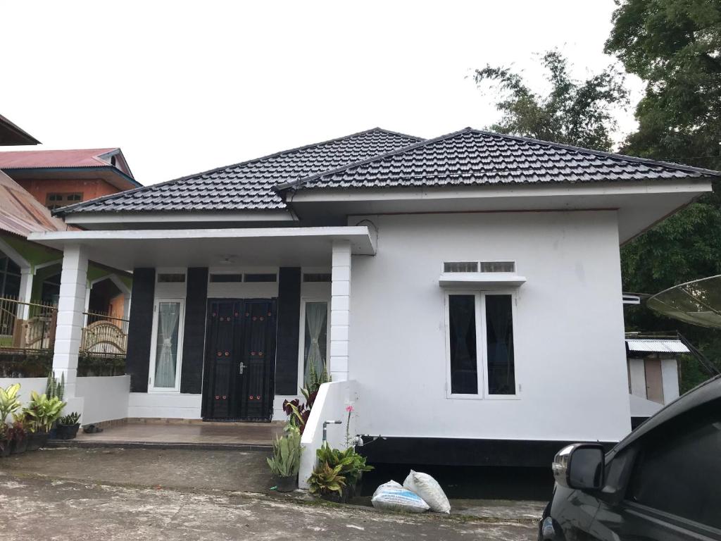 una casa blanca con techo negro en Muda Raya Homestay, en Kotabaru