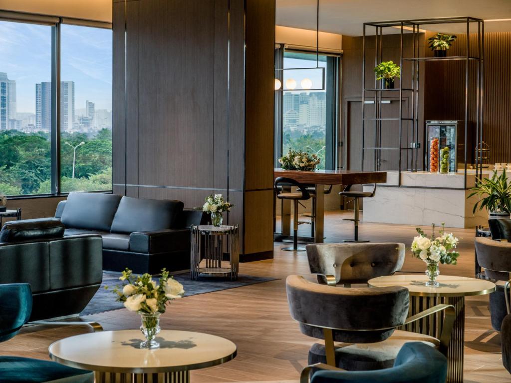 un vestíbulo de hotel con sofás, mesas y ventanas en Fraser Residence Hanoi en Hanoi