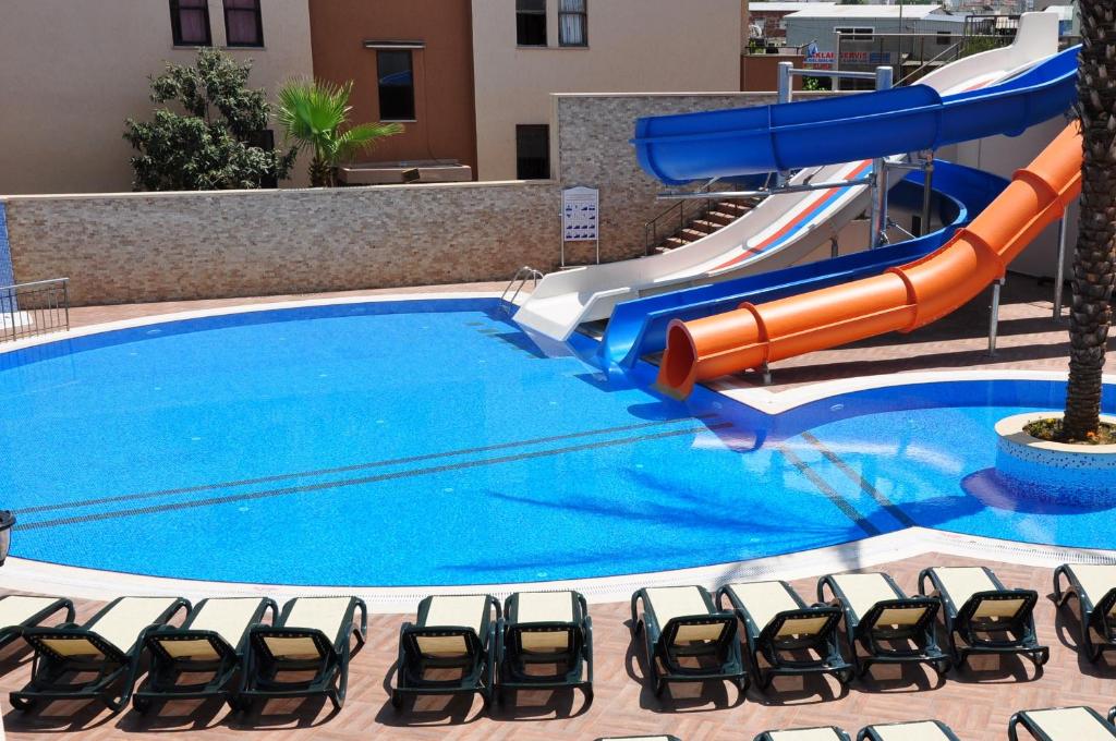 eine Wasserrutsche in einem Pool mit Stühlen daneben in der Unterkunft Almera Park Apart Hotel in Alanya