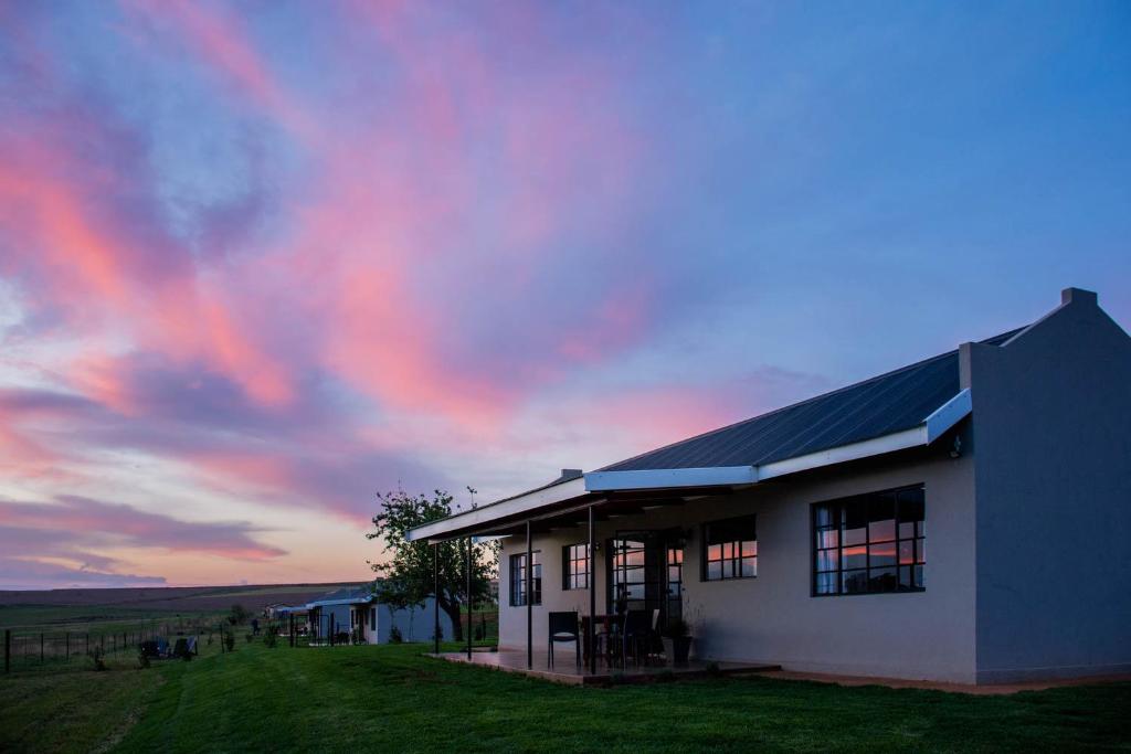 a white building with a sunset in the background at Kezlyn Farm Cottages in Bergville
