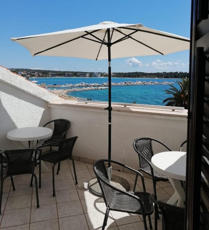 a patio with tables and chairs and an umbrella at Apartmani Ivana in Novalja
