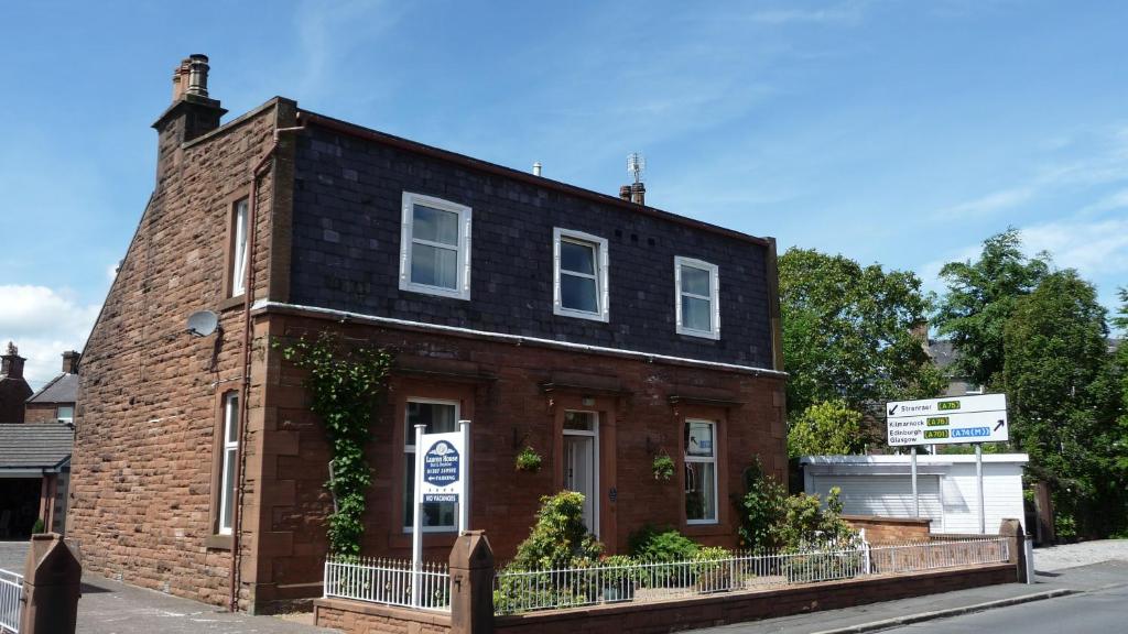 a brick building with a black roof on a street at Lauren House in Dumfries