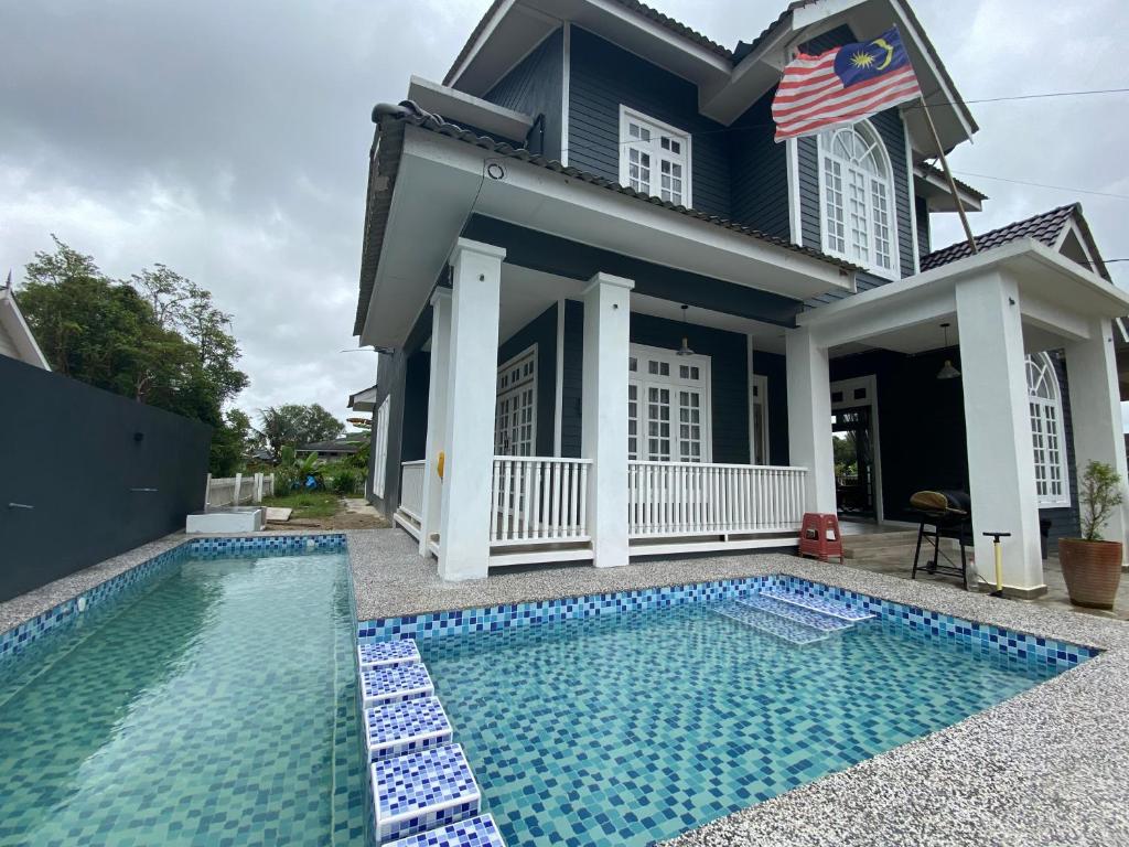 a house with a swimming pool in front of a house at Shafickza Guesthouse in Kuala Terengganu