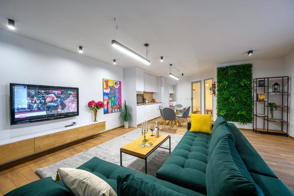 a living room with a green couch and a tv at Гардън Апарт in Blagoevgrad