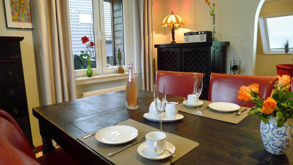 una mesa de madera con platos y tazas y un jarrón con flores en Ferienwohnung Schuberski, en Lipperreihe