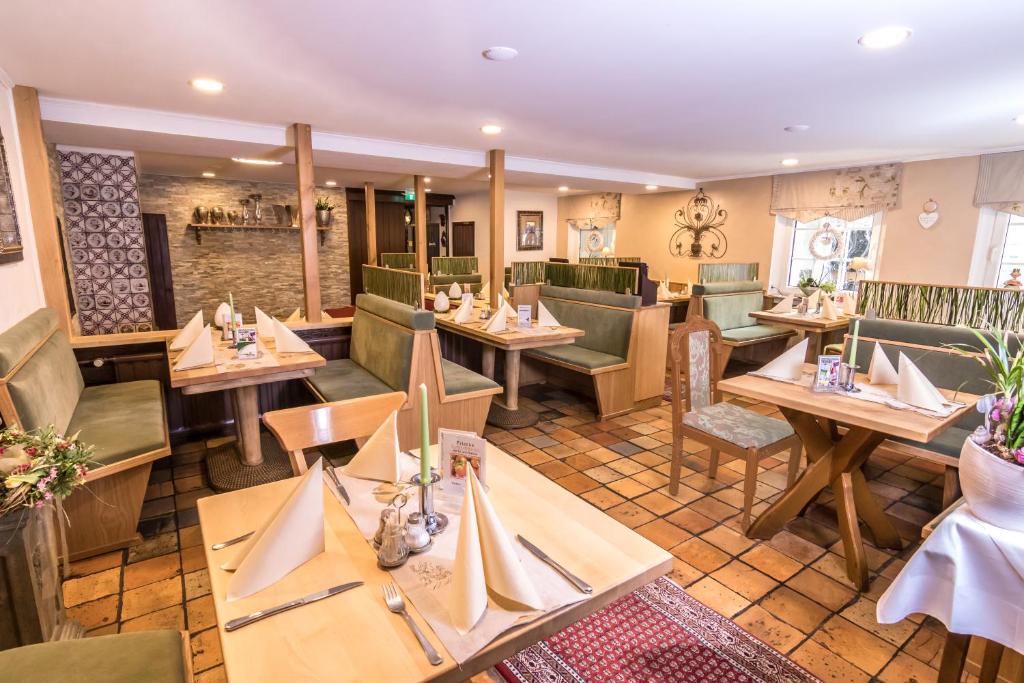 un restaurant avec des tables en bois et des chaises vertes dans l'établissement Hotel Gambrinus Arnsberg, à Arnsberg