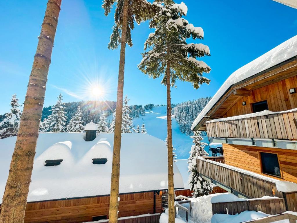 una cabaña en el bosque con nieve en el techo en Sunshine Apartments Golte - Sauna, en Mozirje
