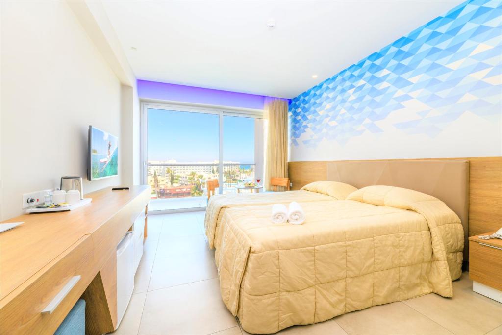 a bedroom with a bed and a desk and a television at Seasons Hotel (Adults Only) in Ayia Napa