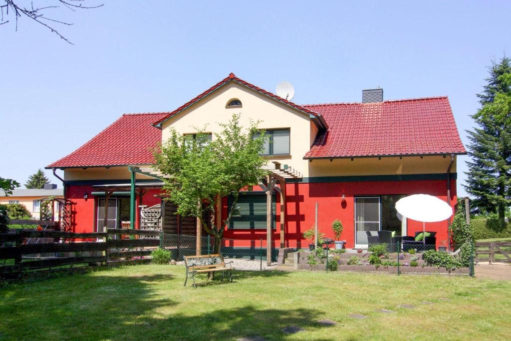 ein rotes und weißes Haus mit einer Bank im Hof in der Unterkunft Apartment, Vogelsang-Warsin in Vogelsang
