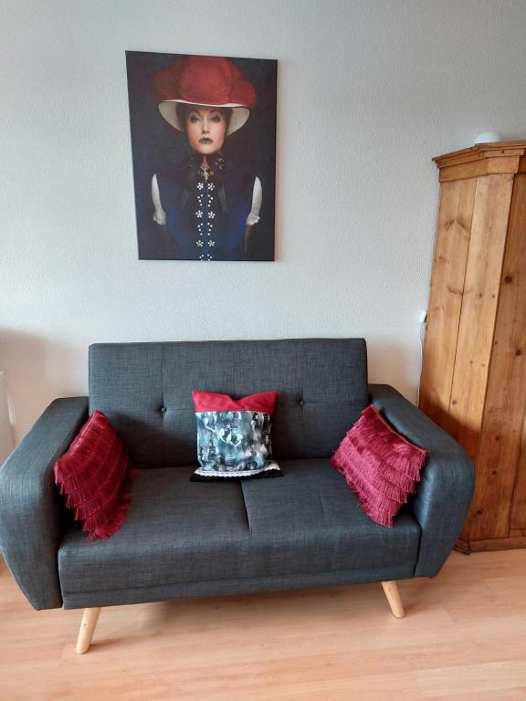a blue couch with a painting of a woman with a hat at Apartment 365 mit Sauna, Schwimmbad und Fitness in Schönwald