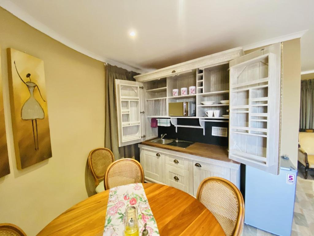 uma cozinha com uma mesa e cadeiras e um frigorífico em Country Lane Farm lodge em Cradock
