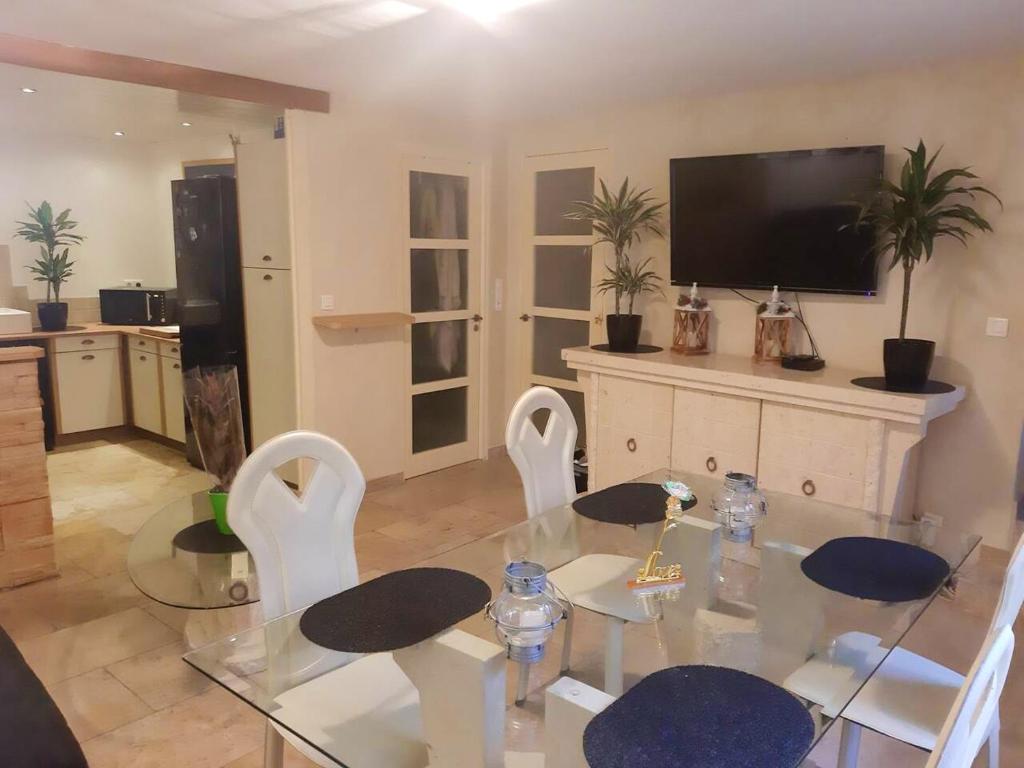 ein Wohnzimmer mit einem Glastisch und weißen Stühlen in der Unterkunft Appartement de 3 chambres avec wifi a Beaucaire in Beaucaire