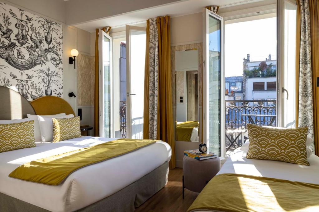 ein Hotelzimmer mit zwei Betten und Balkon in der Unterkunft Grand Hôtel Lévêque in Paris