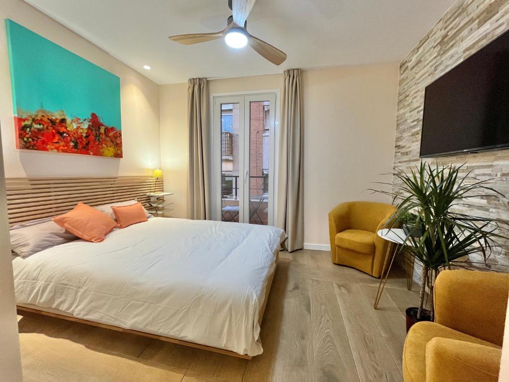 een slaapkamer met een bed, een tv en een stoel bij A Loft You Will Fall In Love With in Tarragona