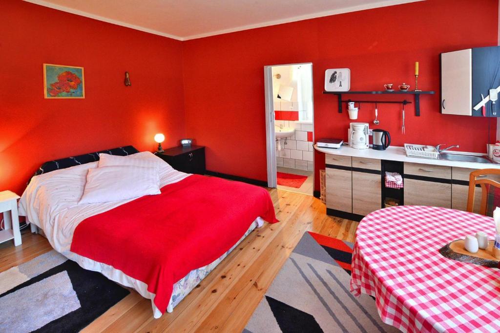 a bedroom with red walls and a bed and a kitchen at Comfortable 2 person holiday apartment in the countryside Drezno in Stare Wierzchowo