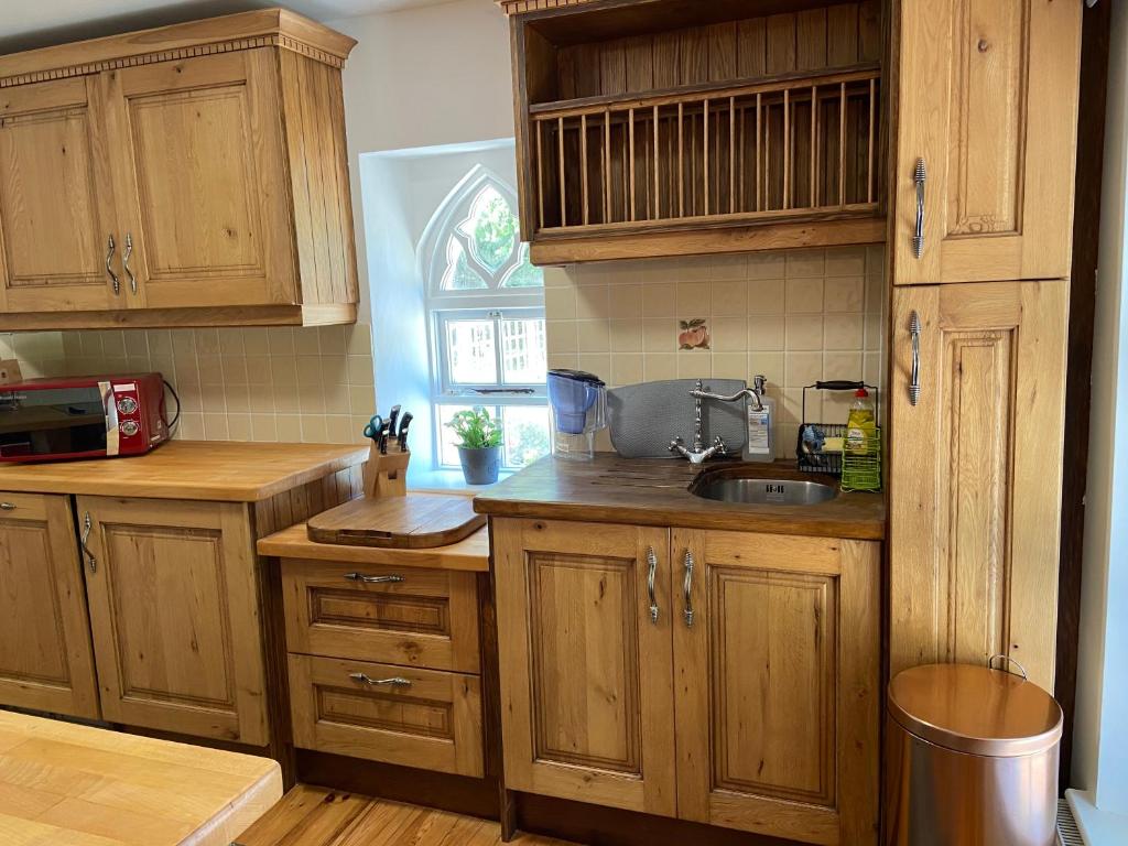 a kitchen with wooden cabinets and a sink at Rathjarney Gatelodge in Wexford