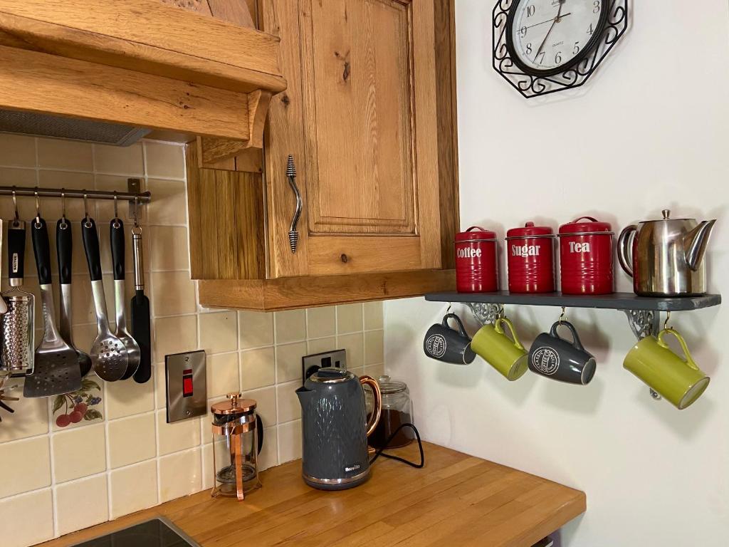 a kitchen counter with red cups and a clock on the wall at Rathjarney Gatelodge in Wexford
