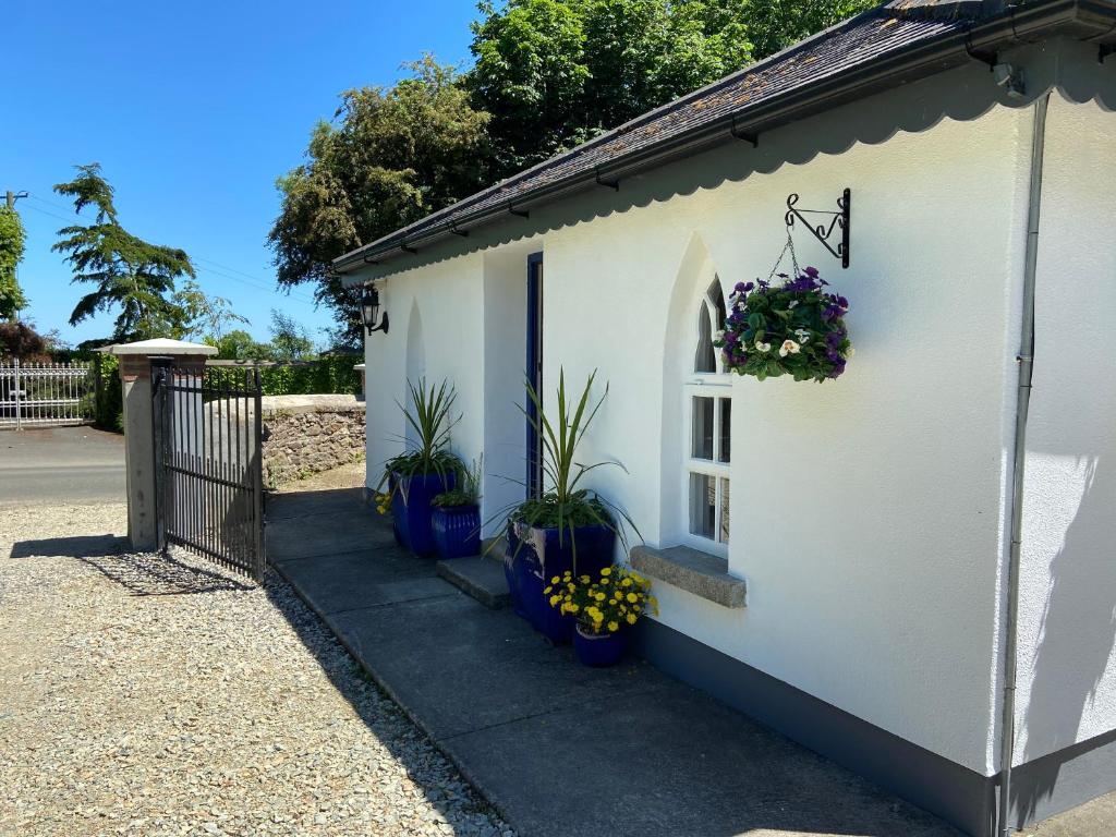 a white building with plants in blue pots on it at Rathjarney Gatelodge in Wexford